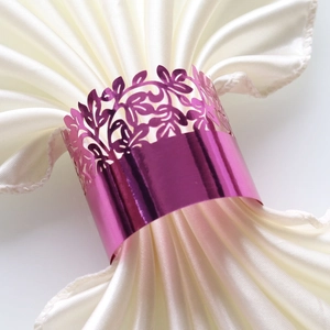 Detail showing rose purple laser-cut metal napkin ring with leaf pattern on white fabric