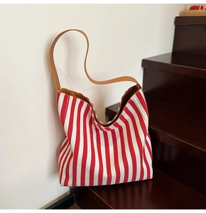Detailed view of red and white striped canvas tote bag with brown leather shoulder strap