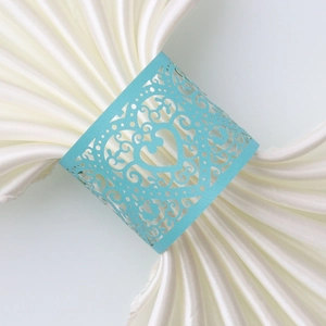 Detailed view of laser-cut blue heart napkin ring on a white silk table napkin