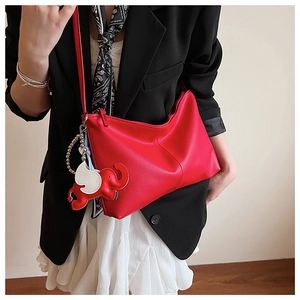 Detail of red lychee pattern tote bag with decorative elephant charm and pleat design