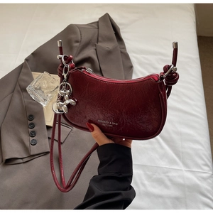 Detail view of burgundy faux oil wax leather dumpling bag with silver balloon dog charm