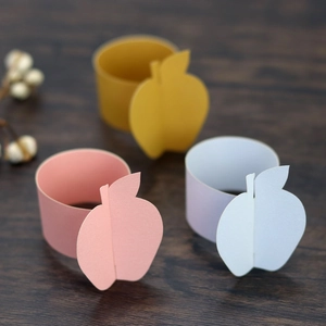 Detailed view of colorful paper apple napkin rings in pink, yellow, and blue colors