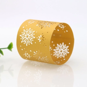 Detail view of laser-cut gold snowflake napkin rings made of shimmering pearlescent paper