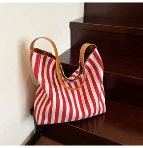 Detail view of red and white striped canvas tote bag with brown leather handles
