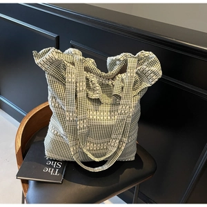 Détail d'un sac cabas en toile vichy vert avec de délicates broderies blanches tressées