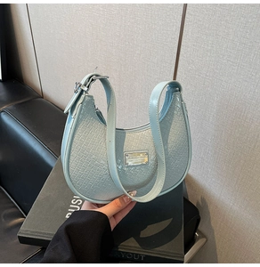 Close-up of light blue faux-crocodile texture shoulder bag with metallic logo detail