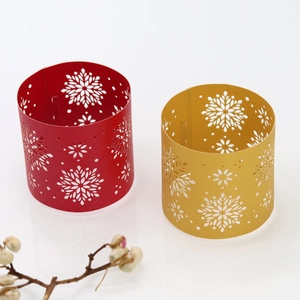 Macro shot of laser-cut paper napkin rings with elegant snowflake patterns in red and gold