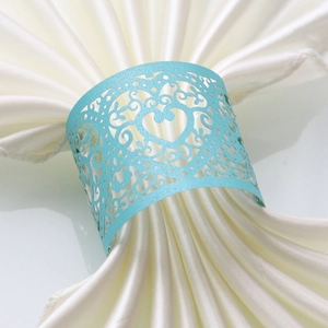 Detail showing laser-cut heart and scroll patterns on a light blue paper napkin ring