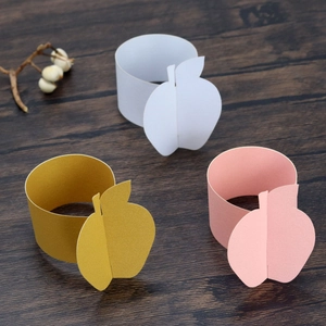 Close-up of golden and colorful apple shaped paper napkin rings on a dark wooden table
