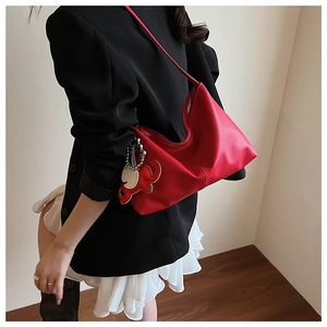 Detail of red pebbled leather hobo bag featuring a distinctive elephant charm ornament