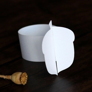 Macro shot of white paper napkin rings featuring a detailed 3D acorn cutout design