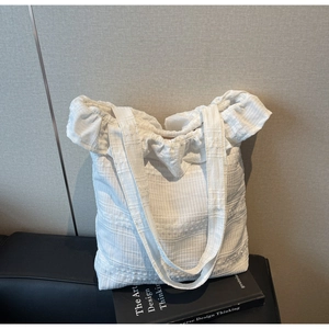 Détail du sac cabas en toile blanche avec texture plissée et bordure à volants