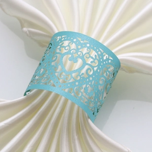 Close-up of light blue laser-cut napkin ring with heart detail on beige satin fabric