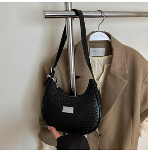 Close-up of black woven leather hobo bag with adjustable strap and silver metal buckle