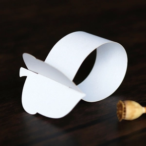 Detailed view of white textured paper napkin ring set against a dark wooden background