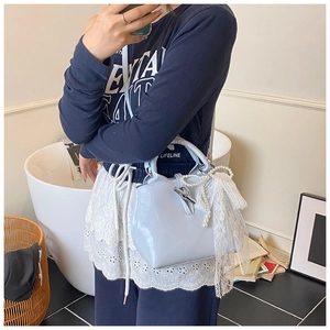 Detail of light blue handbag featuring silver bamboo buckle with lace bow and pearl charm