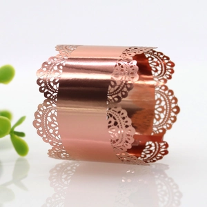 Detail of rose gold metal napkin ring with laser-cut lace pattern and polished finish