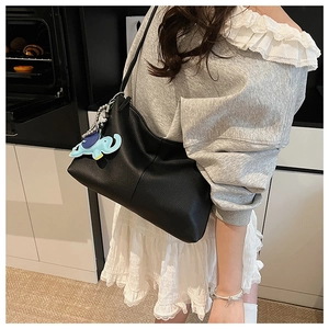 Black pebbled leather tote bag with a light blue elephant charm on the shoulder strap