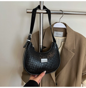 Detail of black woven leather hobo bag with silver metal plaque and smooth leather strap