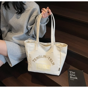 Détail d'un grand sac cabas en toile avec lettres rétro porté sur un escalier en bois