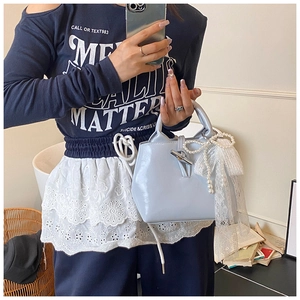 Detail of light blue handbag featuring pearl bow and white lace ribbons in a lifestyle setting