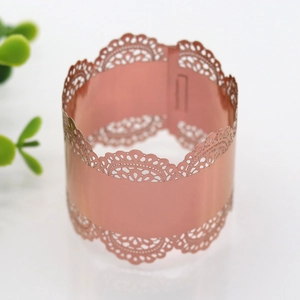 Close-up of laser-cut rose gold napkin ring with intricate lace pattern for parties