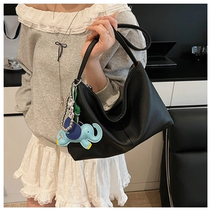 Detail view of black pebbled leather hobo bag featuring a blue elephant charm accessory