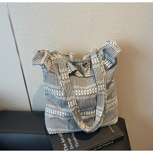 Détail du sac fourre-tout à carreaux noir et blanc avec bords volantés et dentelle