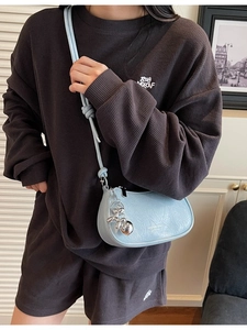 Light blue crossbody hobo bag with leather pleats and a silver dog charm on a model
