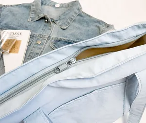 Detail view of the silver metal zipper closure on a light blue canvas tote bag