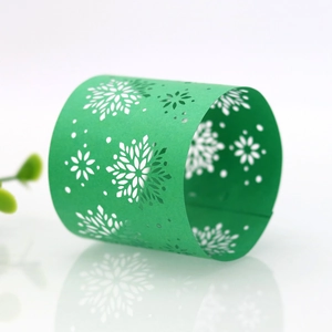 Detailed view of emerald green laser-cut snowflake napkin ring on a reflective surface