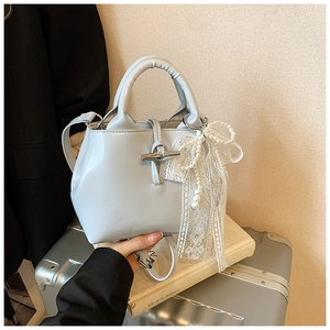 Close-up of light blue PU leather handbag with white lace pearl bow and toggle clasp