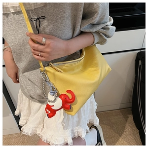 Detail of yellow lychee grain leather tote with a red elephant charm and zip closure