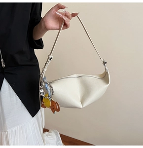 Detail of white hobo bag showing lychee grain leather texture and elephant charm