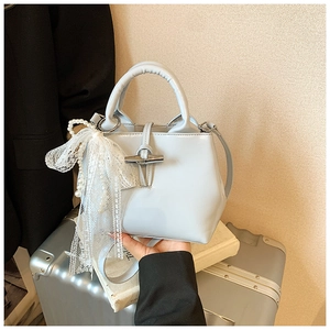 Detail of light blue crossbody bag with bamboo metal clasp and elegant lace pearl charm