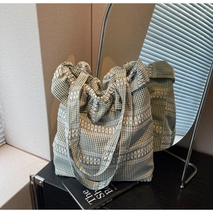 Détail d'un sac cabas en toile à carreaux vert et blanc avec broderie en dentelle blanche