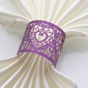 Close-up of a purple laser-cut heart napkin ring on a white satin fabric for weddings