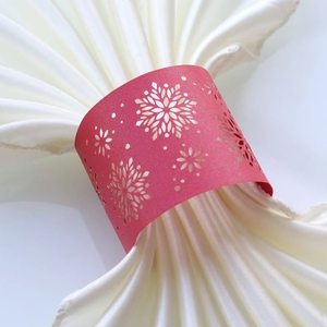 Red laser-cut snowflake paper napkin ring on white satin napkin for Christmas table decor