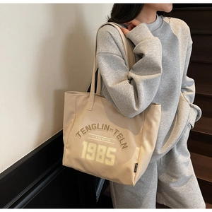 Détail du sac fourre-tout en toile de coton beige avec texte vintage 1985 et bandoulière