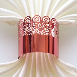 Close-up of rose gold laser-cut lace napkin ring with intricate floral patterns