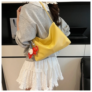 Detail of yellow pebbled leather hobo tote bag featuring a cute elephant charm accessory