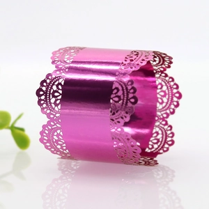 Macro view of metallic rose pink napkin ring with laser-cut lace pattern and reflective finish