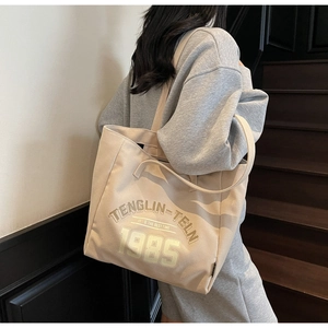 Vue détaillée du sac cabas en toile beige avec typographie rétro sur la bandoulière