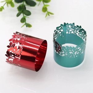Detail of laser-cut metal napkin rings in glossy red and green for festive table decor
