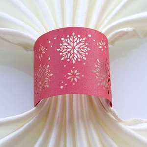 Detailed view of red laser-cut snowflake napkin ring on a white satin folded napkin