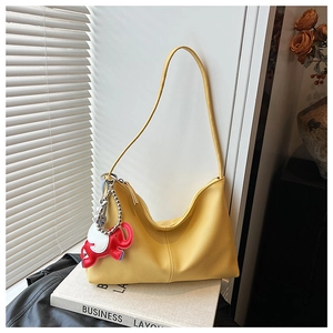 Detail of yellow lychee leather hobo bag featuring a cute red and white elephant charm