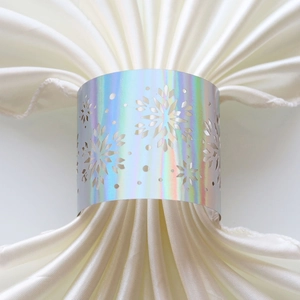 Detailed view of silver laser-cut snowflake napkin ring on a white satin fabric
