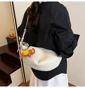 Detailed view of white pebble grain leather dumpling bag with cute elephant charm