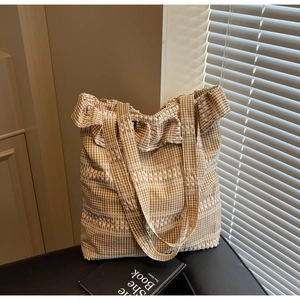 Détail du sac cabas en toile à carreaux marron avec bords à volants et broderies