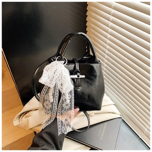 Detail of black glossy bucket bag with silver bamboo buckle and pearl lace charm